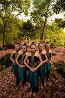 mujeres asiáticas glamorosas con disfraces verdes y maquillaje se alinean juntas en la jungla con hojas marrones en el suelo foto