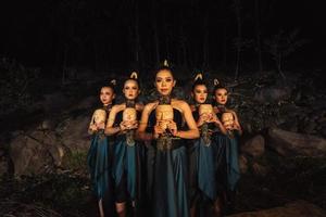 A Group of ethnical women holding a wooden craft mask in their hands while in line inside the wood photo