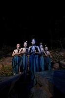 un grupo de mujeres javanesas paradas en el bosque entre las rocas mientras sostienen una máscara de madera foto