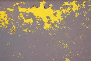 Old yellow grungy metal wall with peeling paint and rusty spots, industrial background photo texture