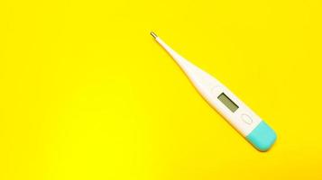 White digital thermometer on yellow background photo