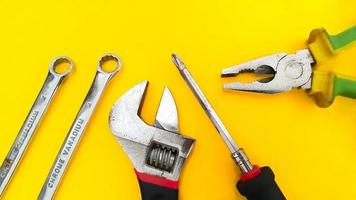 Tool set of wrench, adjustable spanner, pliers and screwdriver isolated on yellow background photo
