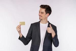 Portrait of Young smiling handsome businessman in casual clothes showing credit card and thumb up isolated over white background photo