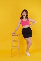 Full length portrait of a beautiful young woman posing isolated over yellow background photo