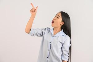 Portrait of young asian woman pointing with two hands and fingers to the side over isolated white background photo