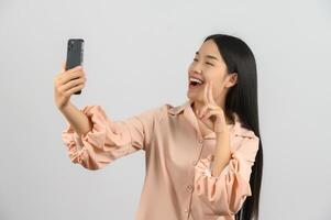 Protrait of Young asian woman expressing surprise while using mobile phone isolated over white background photo