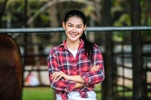 Portrait of Happy young Asian farmer woman crossing arm and looking at camera at dairy cow farm. Agriculture industry, farming, people, technology and animal husbandry concept. photo