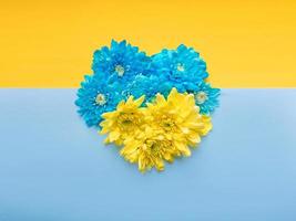 Blue and yellow background with blue and yellow floral heart on it. Stand with Ukraine