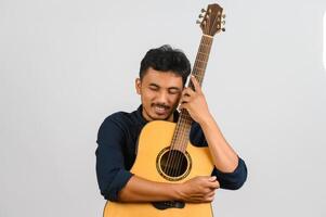 Portrait of Happy young Asian man hugging an acoustic guitar isolated on white background photo