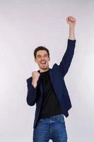 Portrait of happy joyful young businessman standing doing winner gesture clenching fists keeping isolated on white color wall background studio photo