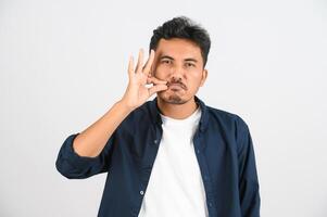 retrato de un joven asiático con camisa azul guardando un secreto aislado de fondo blanco foto