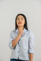 retrato de una joven asiática con camisa azul pensando y mirando hacia arriba aislada de fondo blanco foto