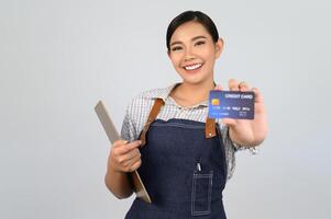 retrato de una joven asiática con uniforme de camarera posando con tarjeta de crédito foto
