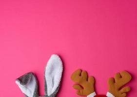 protruding ears of a rabbit mask and brown deer horns on a pink background photo