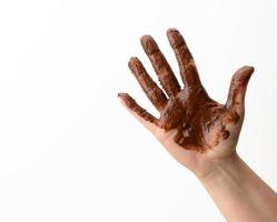 female hand soiled in melted black chocolate on a white background photo