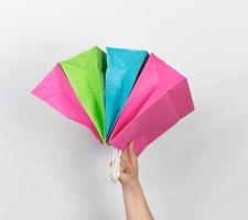 female hand holding four colored paper shopping packaging bags photo