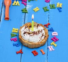 cake with cream and a burning candle photo