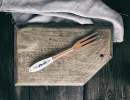 tenedor de madera vintage en una tabla de cortar de cocina marrón rectangular foto