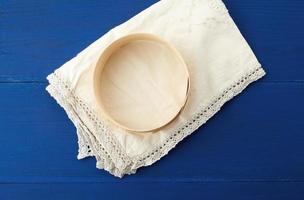 round wooden sieve lies on a white textile kitchen napkin photo