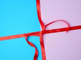 red satin ribbon on a colored background photo