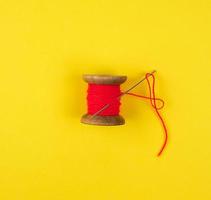 wooden reel with red wool thread and a large needle photo