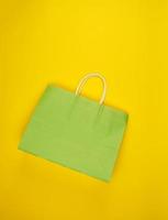 empty green paper shopping bag with a handle on a yellow background photo