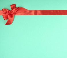 stretched red silk ribbon and tied bow, green background photo
