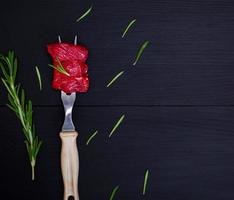 pieces of raw beef on kitchen fork with plastic handle photo