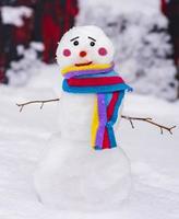 muñeco de nieve divertido con una bufanda colorida y una cara triste foto