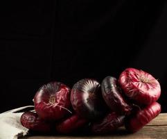 round red onion in husk on a gray linen napkin, black background photo