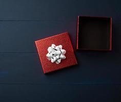 open empty red square cardboard box on a blue wooden background photo