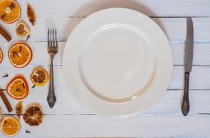 white empty dining plate with cutlery on a white wooden surface photo