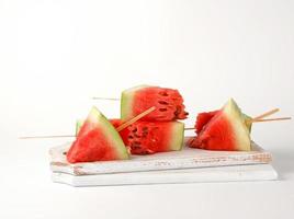 sliced ripe red watermelon with seeds on a wooden white cutting board photo