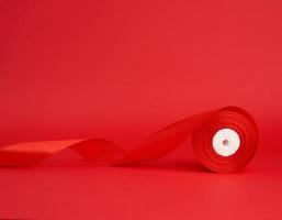 twisted red silk shiny ribbon on a red background, festive design element photo