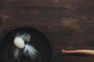 Raw chicken egg in a black cast-iron frying pan photo