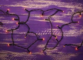 Purple wooden background with electric Christmas garland photo