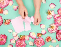 two hands hold an empty pink sheet torn from a notebook photo