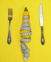 yellow zucchini wrapped in a measuring tape and an iron fork with a knife photo