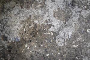 fragmento de un antiguo muro de cemento gris con piedras negras foto
