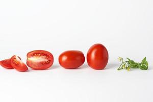 ripe red whole tomatoes and slices, green leaf on a white background photo