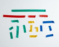 set of torn multicolored rubber pieces of electrical tape glued to a white background photo