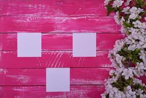 Three blank white sheets on a pink wooden surface photo