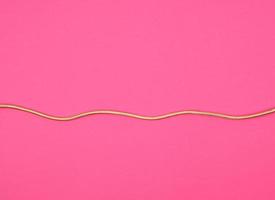 cable dorado para equipos en bobinado textil sobre fondo rosa foto