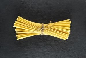 raw spaghetti tied with a rope on a black background photo