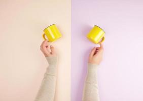 two female hands are holding yellow ceramic cups on a colored background photo
