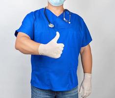 male doctor in blue uniform and latex white gloves shows right hand gesture like photo