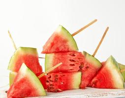 sliced ripe red watermelon with seeds on a wooden white cutting board photo