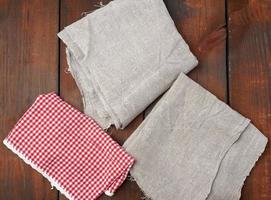 white red checkered kitchen towel and gray linen napkins on a brown wooden background photo