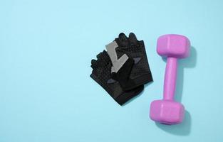 black ports gloves, pair of purple dumbbells on a blue background, healthy lifestyle photo