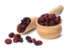 a bunch of dried cranberries in a wooden bowl on a white background. Delicious berry photo